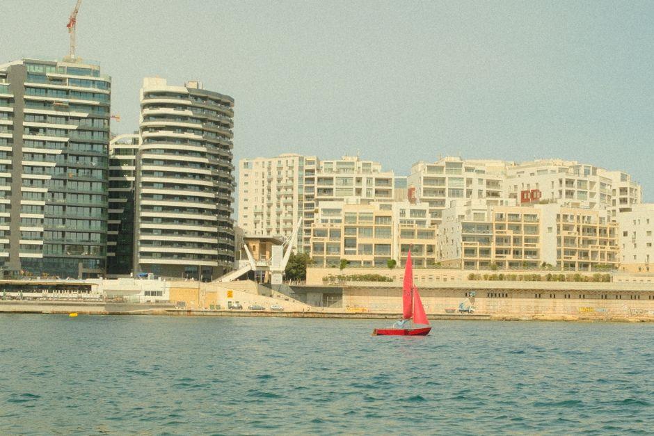 Bright Red Sailboat in Maltese Coastal Waters