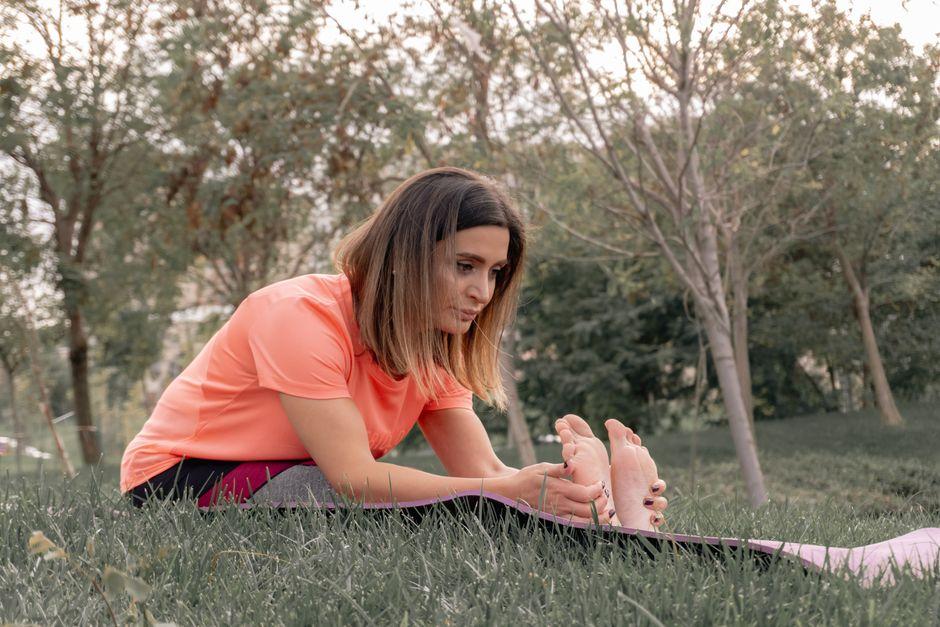Woman Stretching in Park during Daytime Exercise